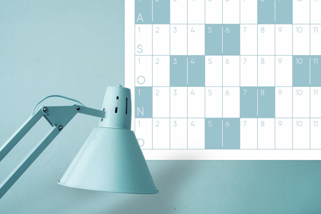 A wall calendar beside a blue desk lamp