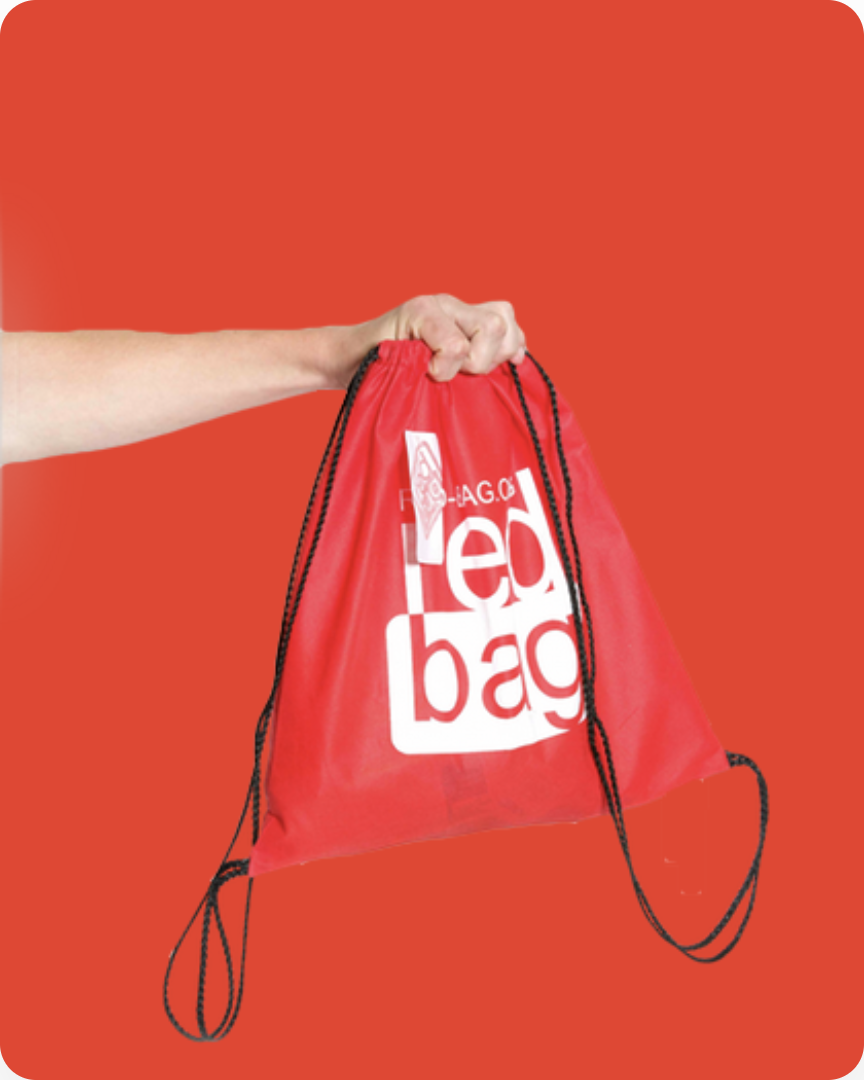 A hand holding out a red drawstring bag